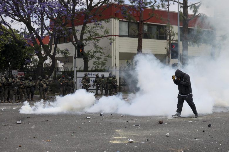 Un manifestante camina a través del humo de granadas de humo aturdidoras disparadas por agentes federales cerca de un Home Depot después de que el Servicio de Inmigración y Control de Aduanas (ICE) realizara una redada en Paramount, California, EE.UU. EFE/ALLISON DINNER
