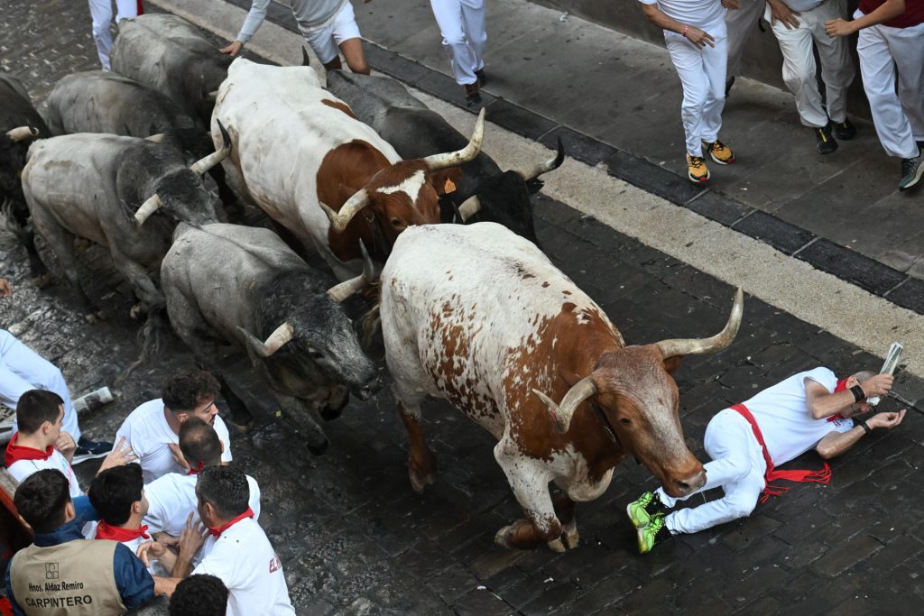 Uno de los mozos cae al paso de los toros de la ganadería de José Escolar en el sexto encierro de los Sanfermines, este 12 de julio en Pamplona. EFE/José Luis Larrión