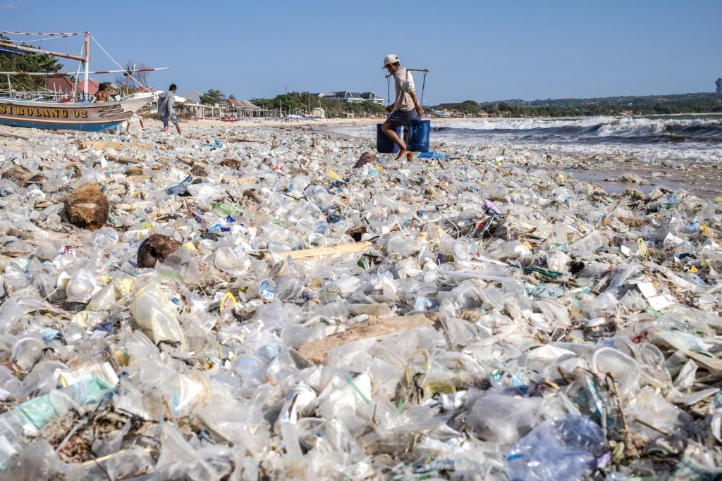 Un hombre cargando cubos camina por una playa llena de montones de escombros y residuos plásticos en la playa de Kedonganan en Bali, Indonesia, en una imagen de archivo. EFE/EPA/MADE NAGI