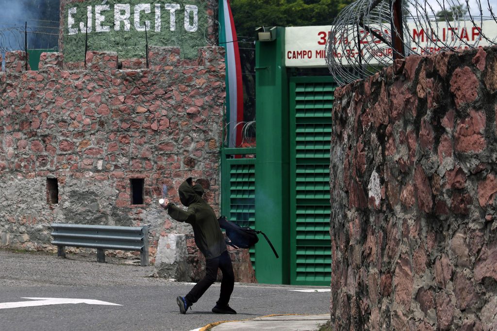 Encapuchados lanzan petardos a la entrada de la 35a Zona Militar este lunes, durante una protesta en contra del Ejército en el marco del décimo primer aniversario de la desaparición de los 43 normalistas de Ayotzinapa, en Chilpancingo (México). EFE/ José Luis De La Cruz