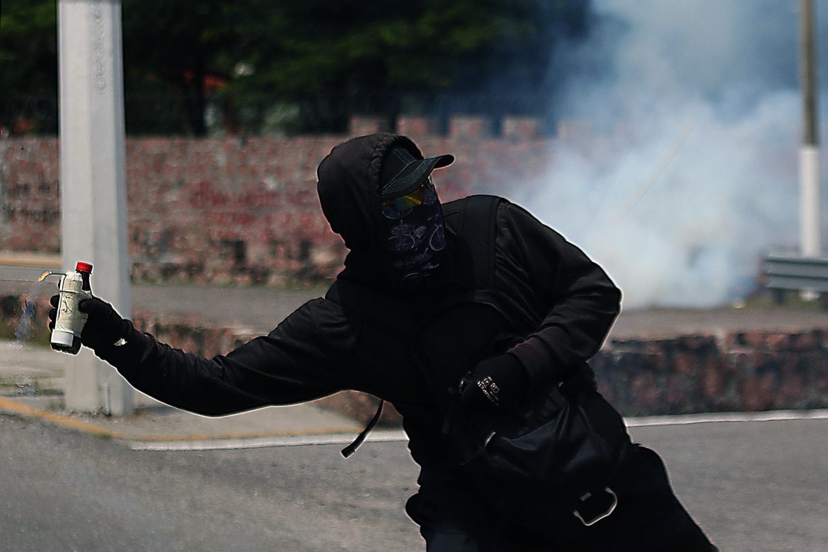 Encapuchados lanzan petardos a la entrada de la 35a Zona Militar este lunes, durante una protesta en contra del Ejército en el marco del décimo primer aniversario de la desaparición de los 43 normalistas de Ayotzinapa, en Chilpancingo (México). EFE/ José Luis De La Cruz