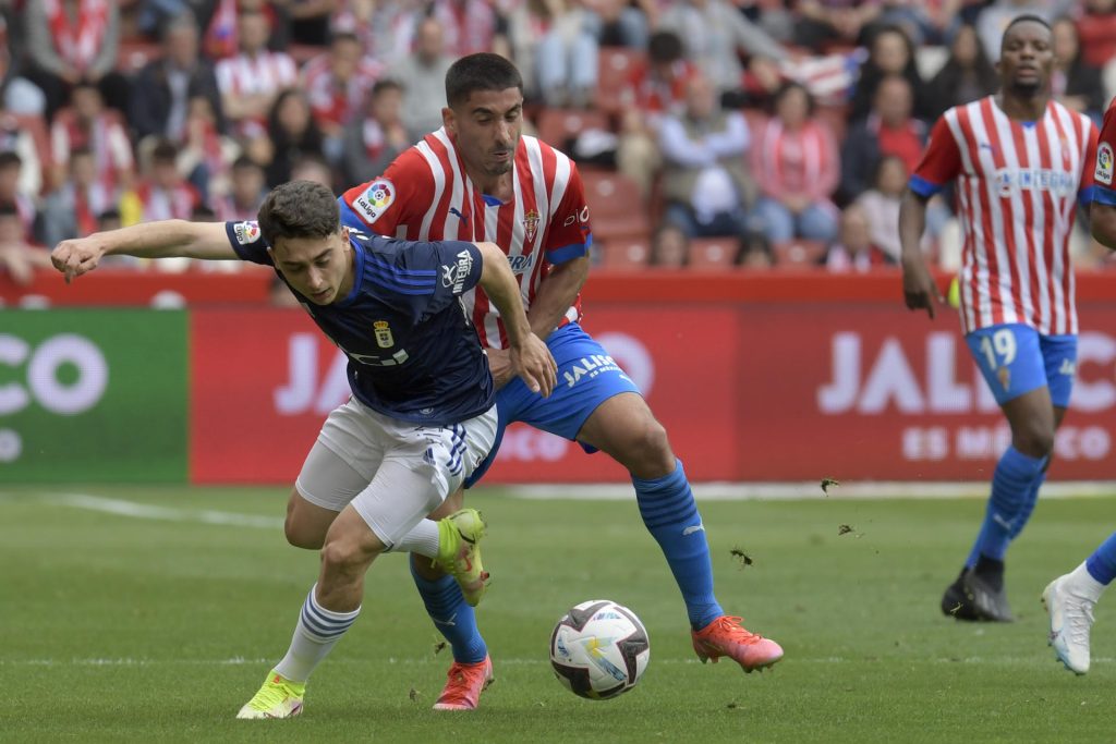 José Ángel Valdés 'Cote' (C) pugna por el balón con el centrocampista del Oviedo Raúl Moro (I) en un partido de Liga disputado el 13 d mayo de 2023 en El Molinón. EFE/Eloy Alonso