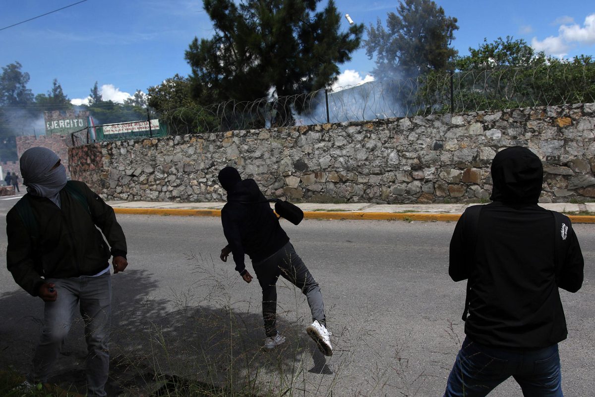 Encapuchados lanzan petardos a la entrada de la 35a Zona Militar este lunes, durante una protesta en contra del Ejército en el marco del décimo primer aniversario de la desaparición de los 43 normalistas de Ayotzinapa, en Chilpancingo (México). EFE/ José Luis De La Cruz