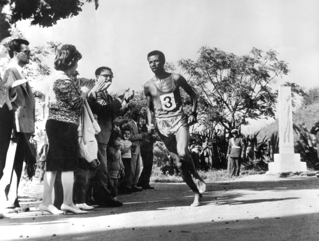 Atenas (Grecia), 9-5-1961.- El atleta etíope y campeón olímpico, Bikila Abebe, pasa ante la tumba del primer corredor de maratón, Phidippides, durante la Carrera Internacional de Maratón, que ha ganado frente a atletas de todo el mundo. EFE/voo/ARCHIVO