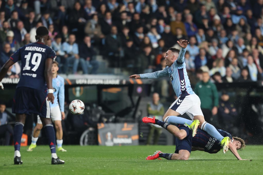 El delantero del Celta Iago Aspas (d, arriba) cae ante Nicolás Tagliafico (d, abajo), del Olympique, durante el partido de ida de los octavos de final de la Liga Europa que Celta y Olympique de Lyon disputan este jueves en el estadio de Balaídos, en Vigo. EFE/Salvador Sas 